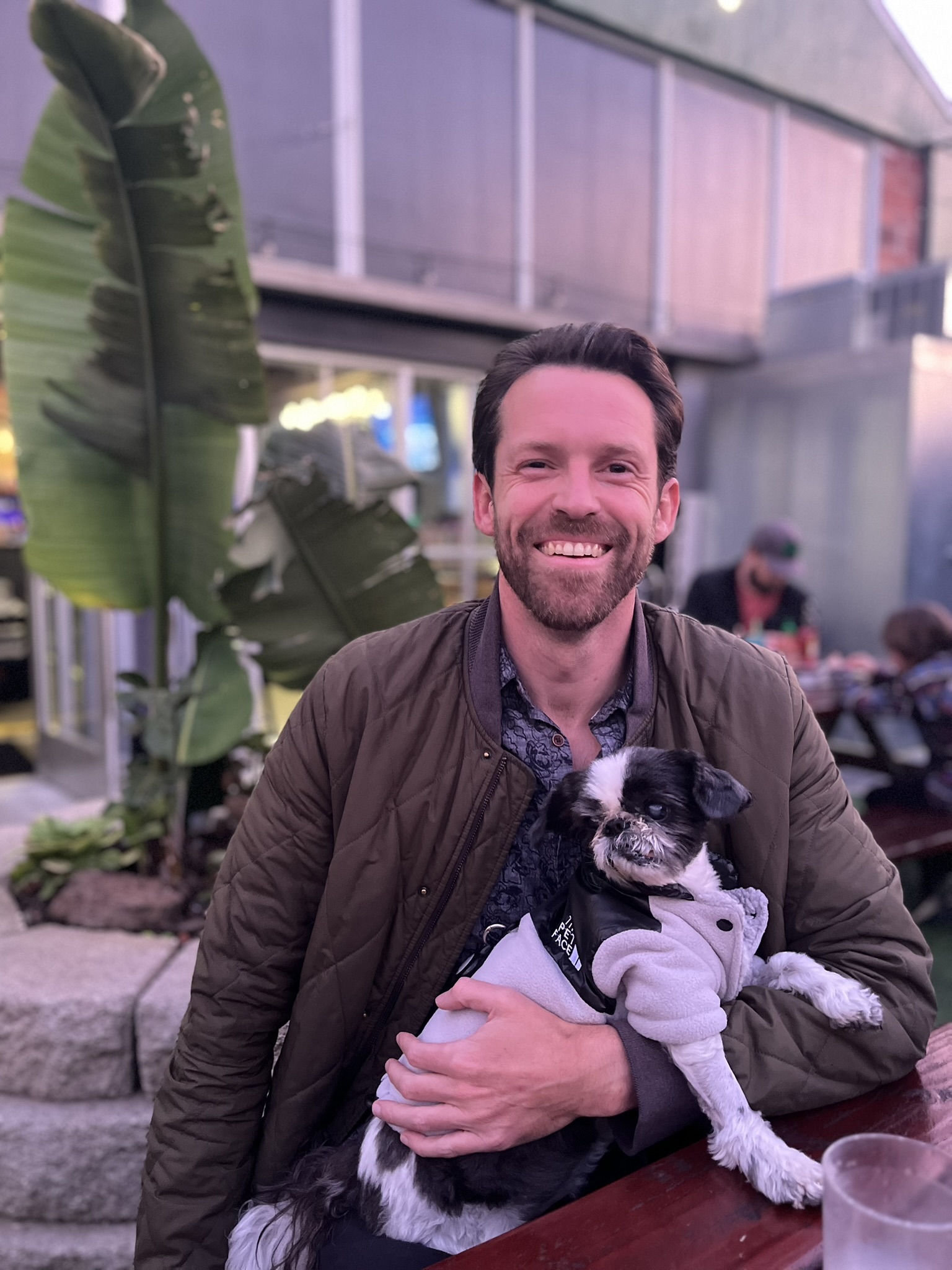 Mike smiling while holding Zuki at a café