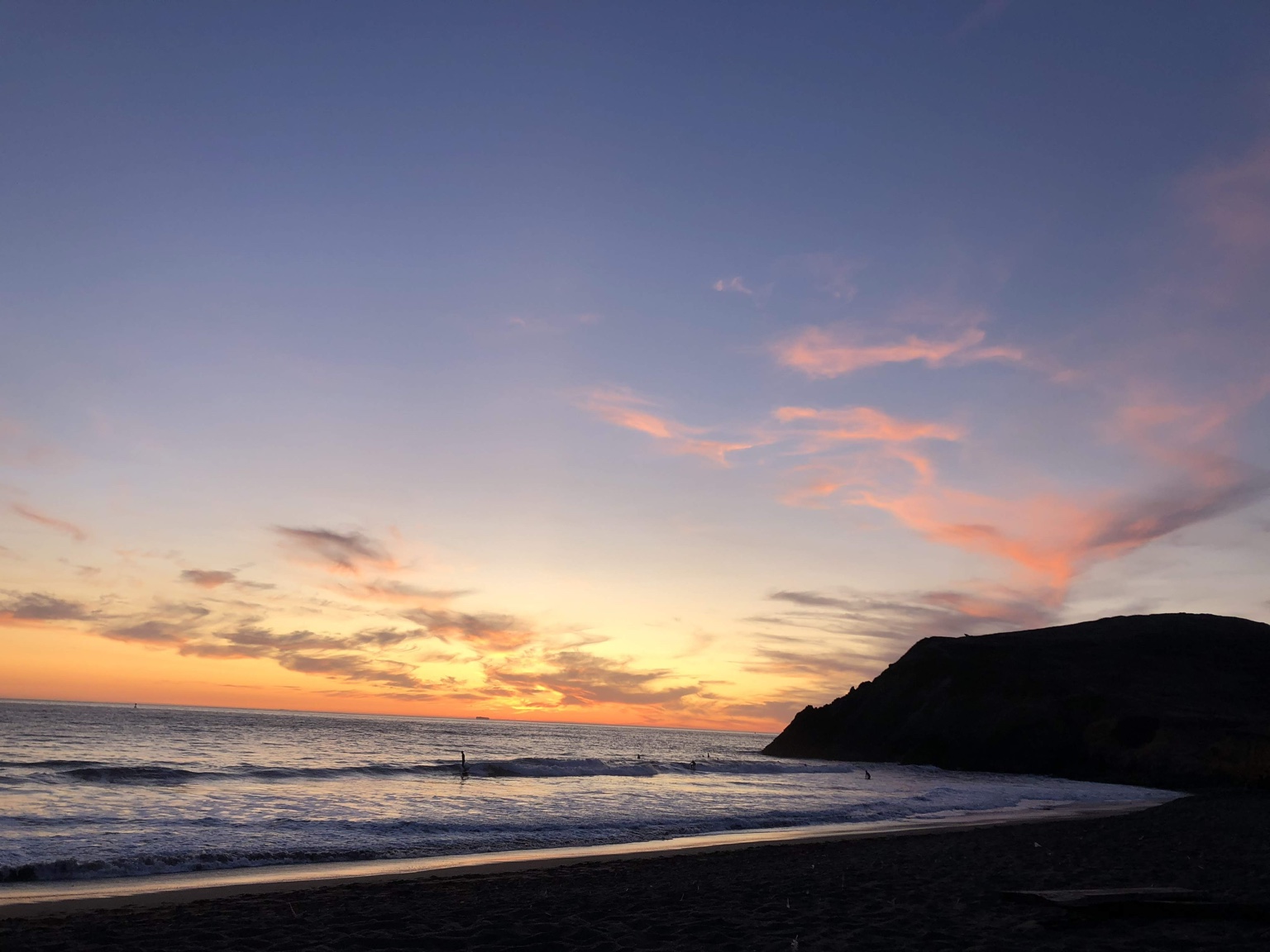 Cliffs and beach beneath an orange sunset at Rodeo Beach