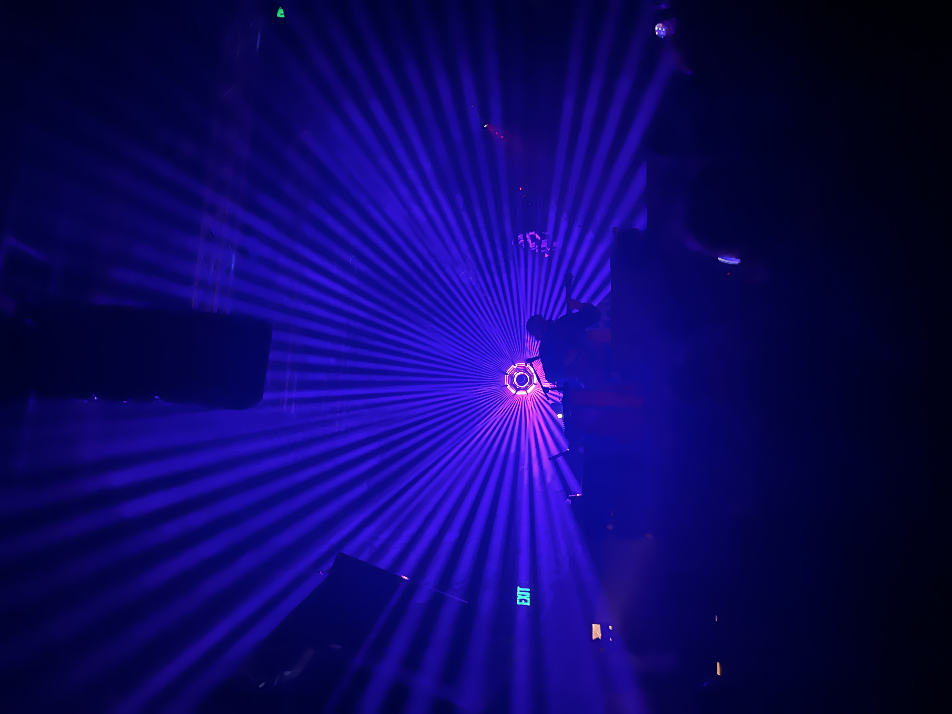 Blue and violet beams radiating through a dark music venue